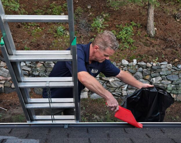Photo: gutters are cleaned of debris by the PEAK Window Cleaning company.